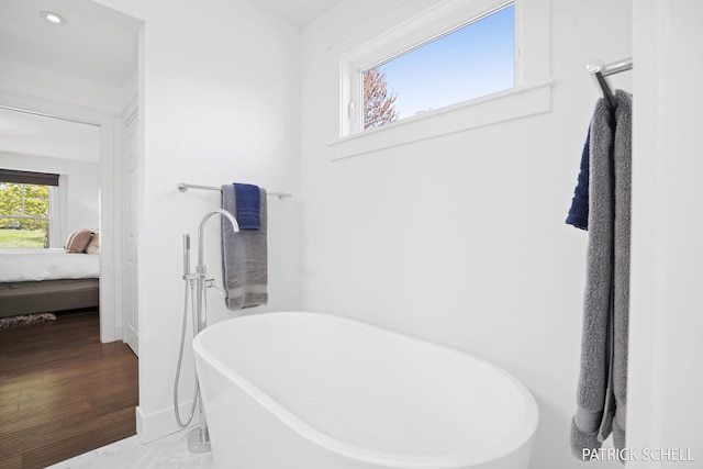 bathroom with connected bathroom, a freestanding tub, recessed lighting, and baseboards