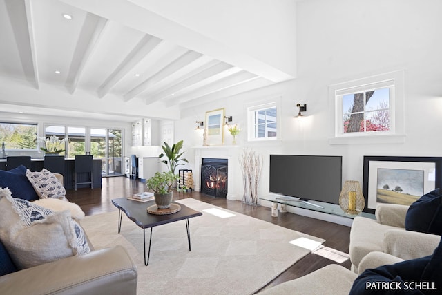 living room featuring beam ceiling, wood finished floors, a warm lit fireplace, and recessed lighting