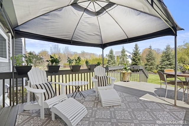 wooden terrace featuring outdoor dining area and a gazebo