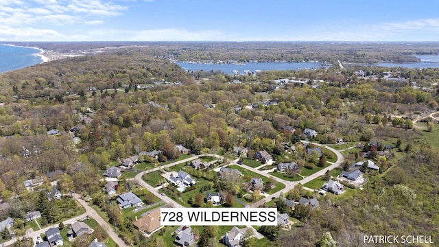 aerial overview of property's location with a nearby body of water and a heavily wooded area