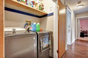 laundry area with washing machine and dryer, wood finished floors, and baseboards