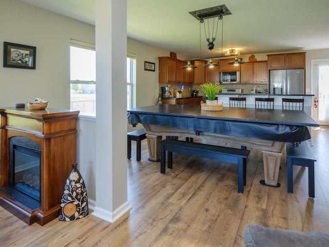 dining room featuring light wood finished floors, baseboards, and a glass covered fireplace