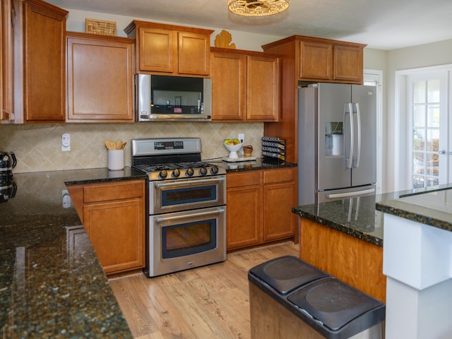 kitchen featuring appliances with stainless steel finishes, light wood finished floors, brown cabinets, and backsplash