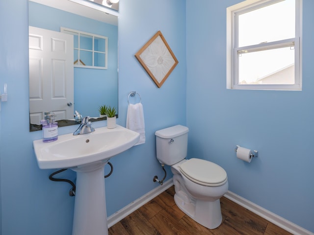 bathroom with toilet, wood finished floors, and baseboards