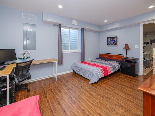 bedroom with wood finished floors, electric panel, a desk, recessed lighting, and baseboards