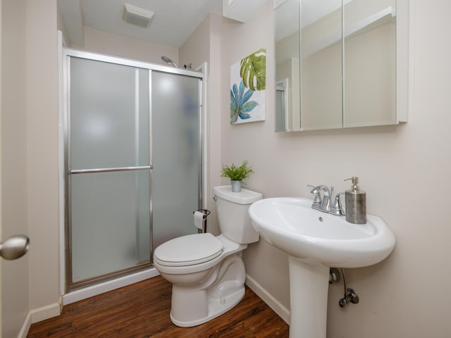 bathroom with wood finished floors, a shower stall, and toilet