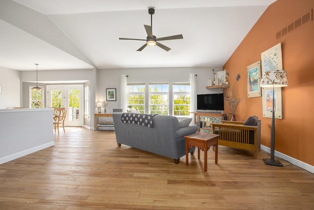 living area with lofted ceiling, a ceiling fan, plenty of natural light, light wood-type flooring, and baseboards