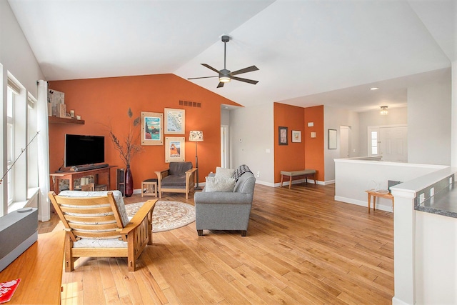 living room with lofted ceiling, a ceiling fan, light wood-type flooring, and baseboards