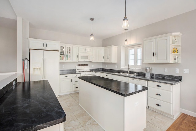 kitchen featuring white appliances, a sink, white cabinetry, hanging light fixtures, and a center island