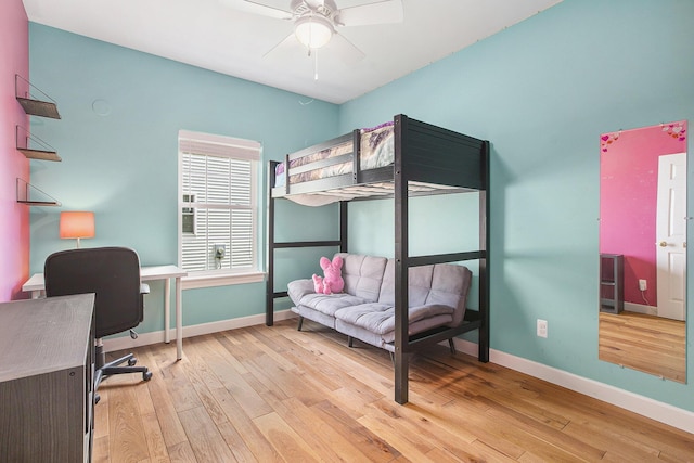 bedroom with light wood-style floors, baseboards, an office area, and a ceiling fan