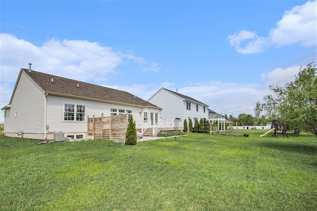 rear view of property featuring a deck, a playground, a yard, and central air condition unit