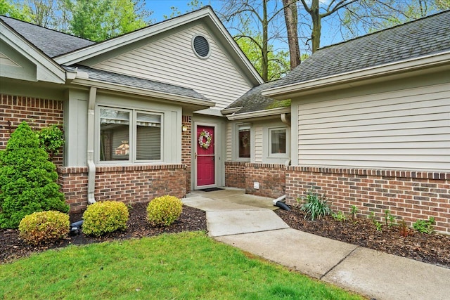 property entrance featuring brick siding and roof with shingles