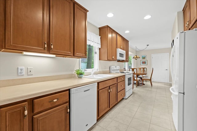 kitchen with white appliances, a sink, brown cabinetry, light countertops, and recessed lighting