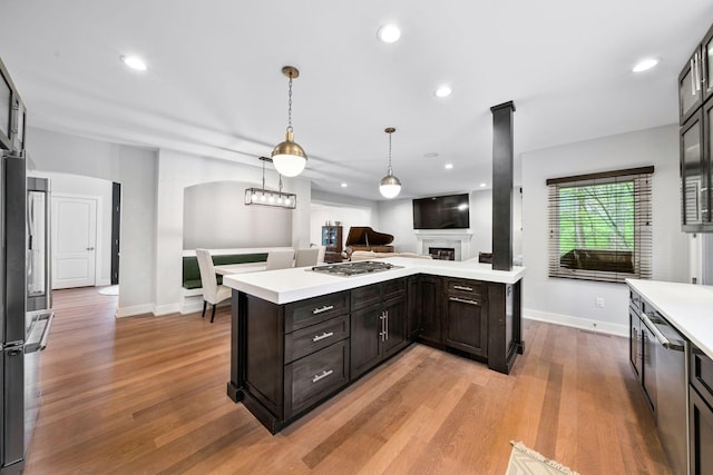 kitchen with light countertops, baseboards, light wood-type flooring, a fireplace, and recessed lighting