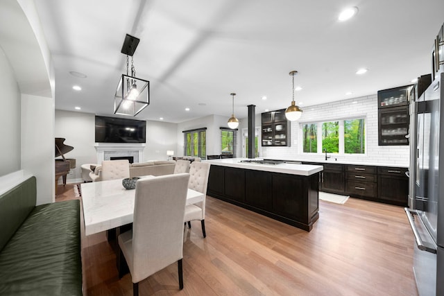 dining space with a fireplace, light wood-style floors, and recessed lighting