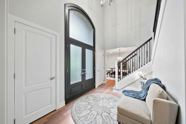 foyer featuring a chandelier, stairway, wood finished floors, a high ceiling, and baseboards