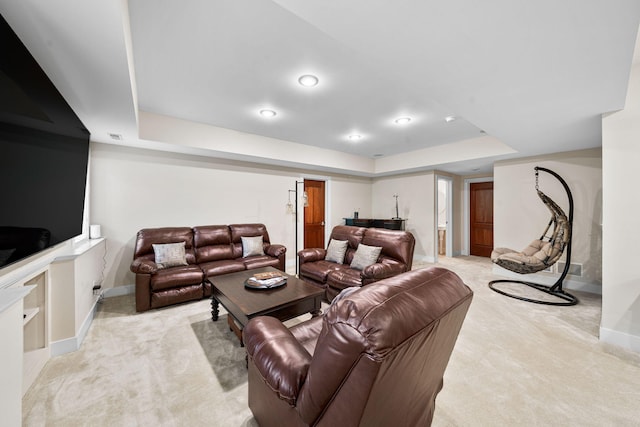 living room featuring a raised ceiling, baseboards, and light carpet