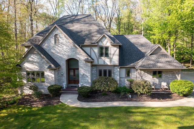 view of front of property with french doors, a shingled roof, a front lawn, and stone siding