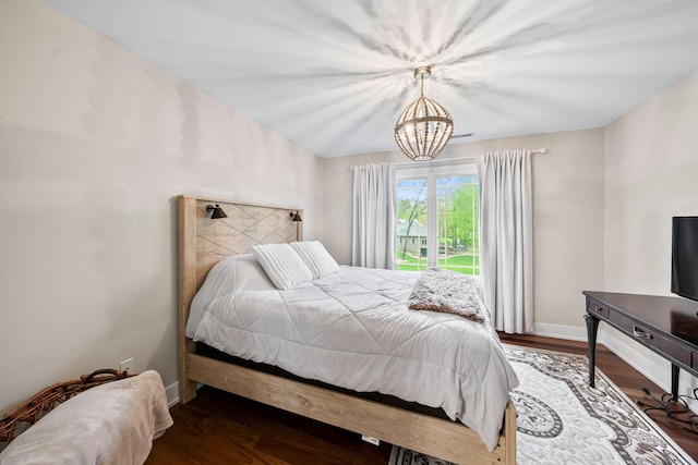 bedroom featuring a chandelier, wood finished floors, and baseboards