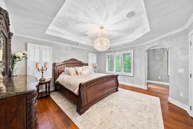 bedroom featuring a tray ceiling, dark wood-style flooring, arched walkways, baseboards, and crown molding