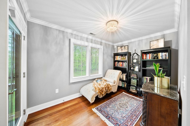 sitting room with healthy amount of natural light, ornamental molding, wood finished floors, and baseboards