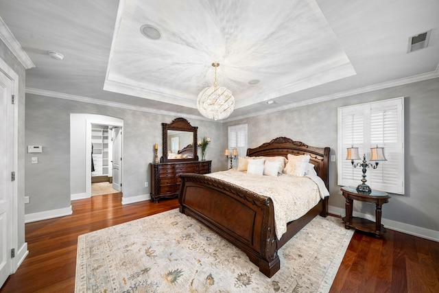 bedroom with a raised ceiling, wood finished floors, a chandelier, baseboards, and ornamental molding