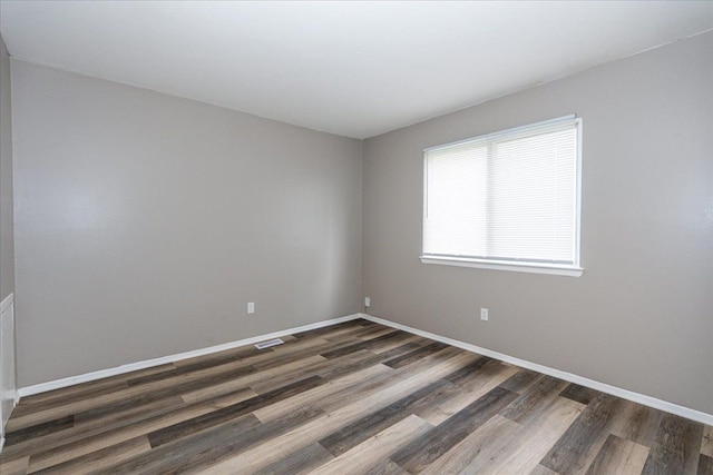 empty room with dark wood-type flooring and baseboards