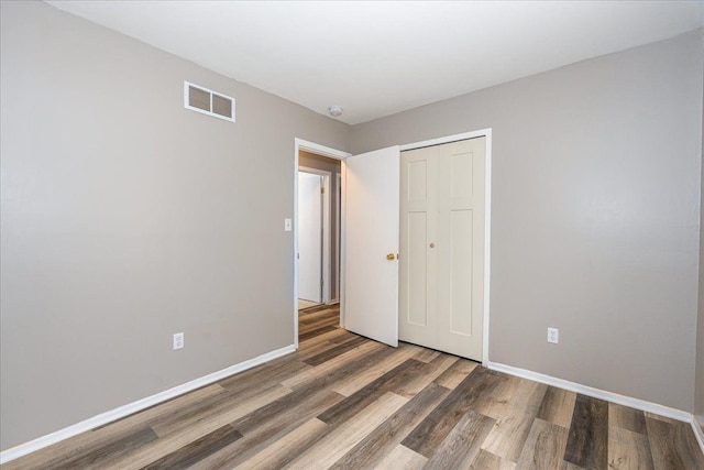 unfurnished bedroom featuring wood finished floors, a closet, and baseboards