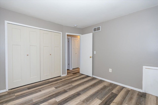 unfurnished bedroom with wood finished floors, a closet, and baseboards
