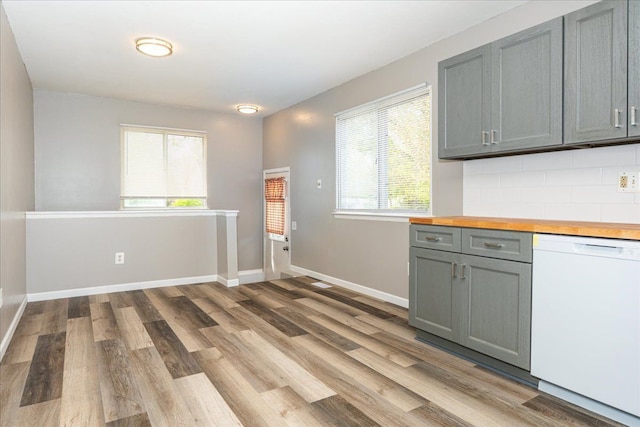 kitchen featuring white dishwasher, gray cabinets, butcher block countertops, light wood finished floors, and tasteful backsplash
