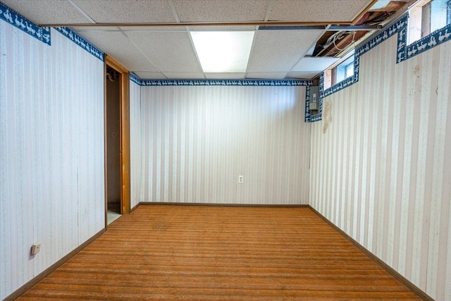 finished basement with wallpapered walls, a paneled ceiling, and carpet floors
