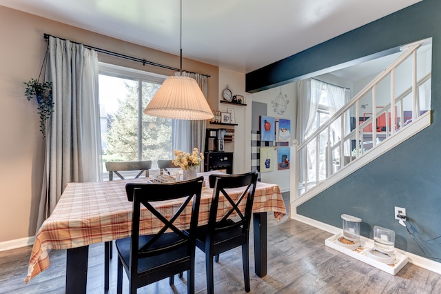 dining area with baseboards, wood finished floors, and stairway
