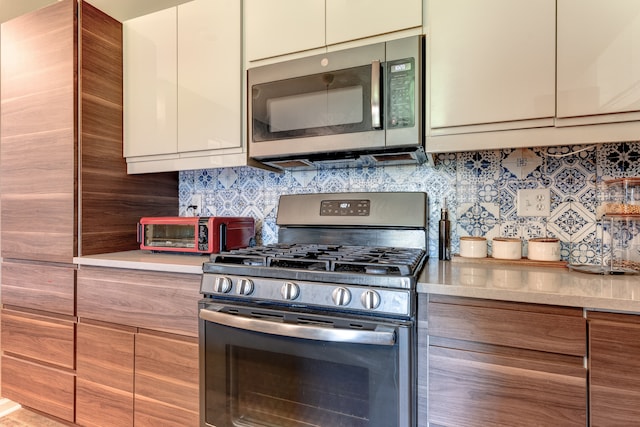 kitchen featuring stainless steel appliances, light countertops, tasteful backsplash, and modern cabinets