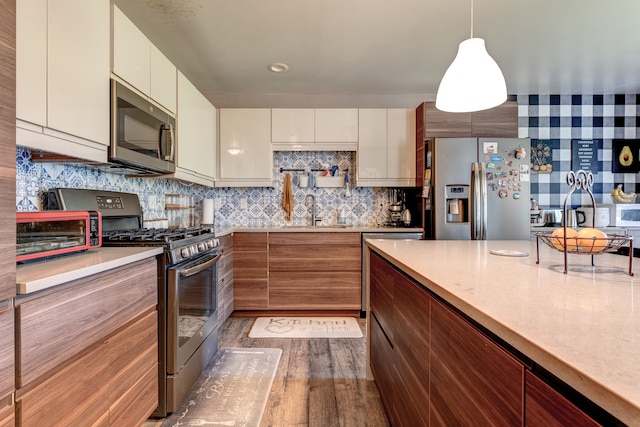kitchen featuring stainless steel appliances, a sink, light countertops, and dark wood-style flooring