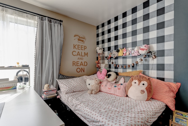 bedroom featuring an accent wall and wallpapered walls