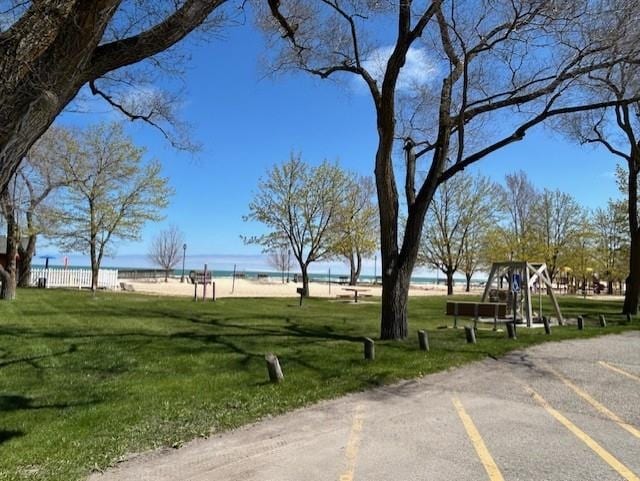 view of property's community featuring a lawn and view of water and beach