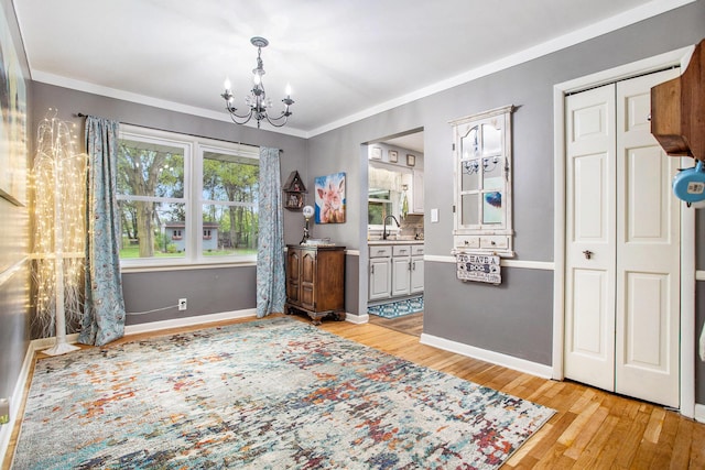 dining room featuring a chandelier, light wood-style floors, baseboards, and crown molding
