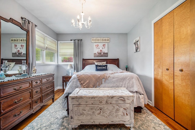 bedroom featuring a chandelier, wood finished floors, baseboards, and a closet
