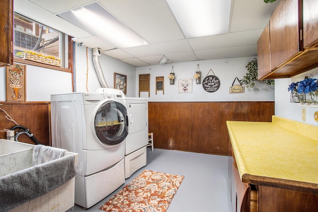 washroom featuring independent washer and dryer, cabinet space, wainscoting, and wooden walls