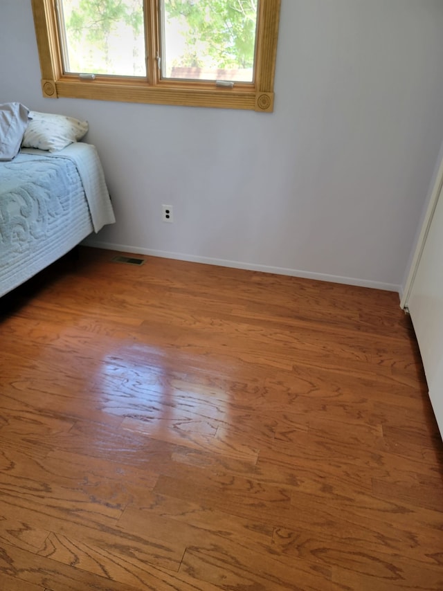 bedroom featuring multiple windows, wood finished floors, and baseboards