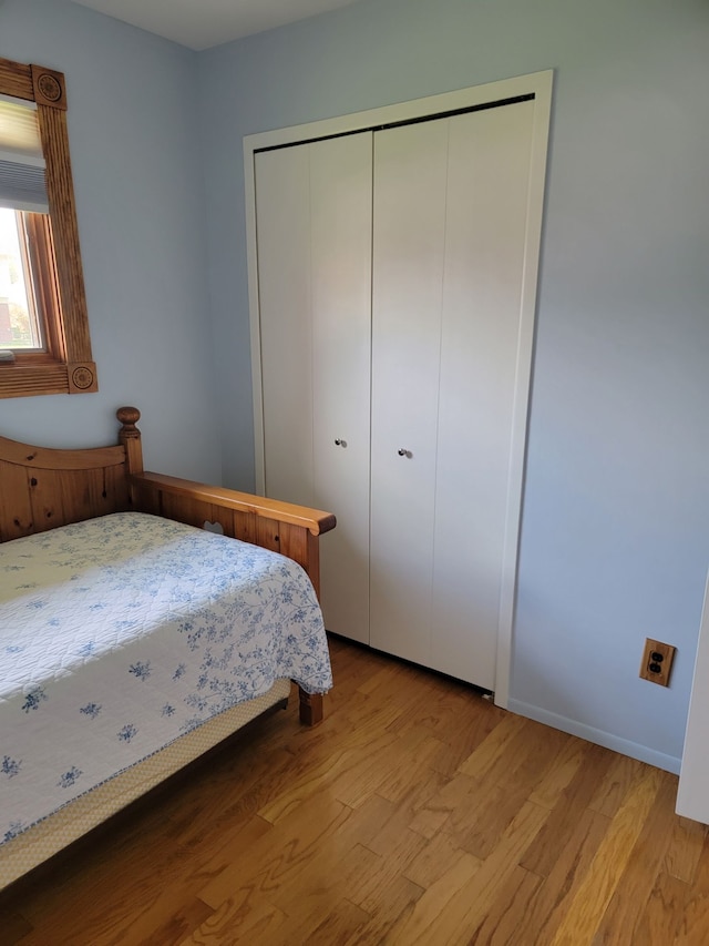 bedroom with wood finished floors, a closet, and baseboards