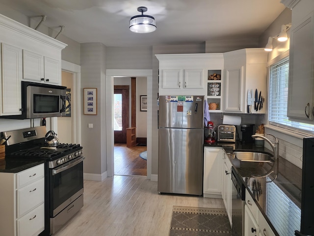 625 Leonard St NE, Grand Rapids, MI 49503 - kitchen featuring stainless steel appliances, open shelves, a sink, dark countertops, and plenty of natural light