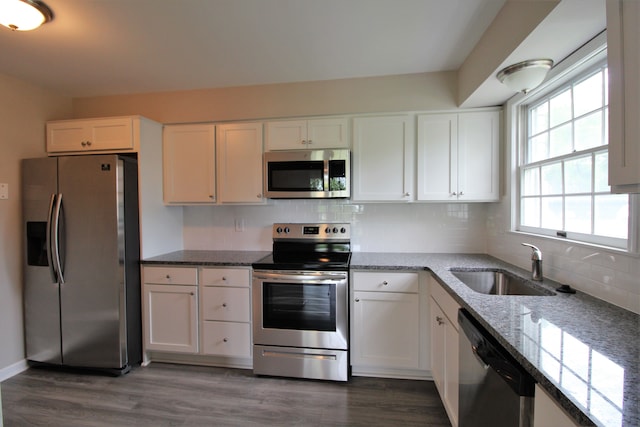 kitchen with appliances with stainless steel finishes, a sink, light stone counters, and white cabinetry