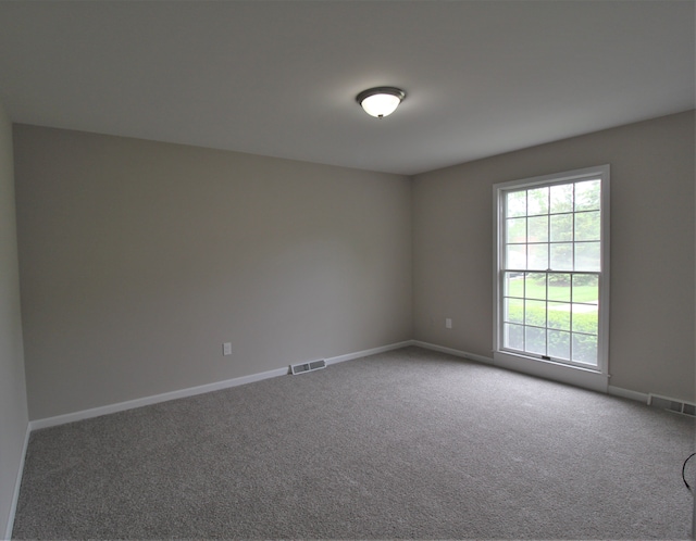 carpeted empty room featuring baseboards