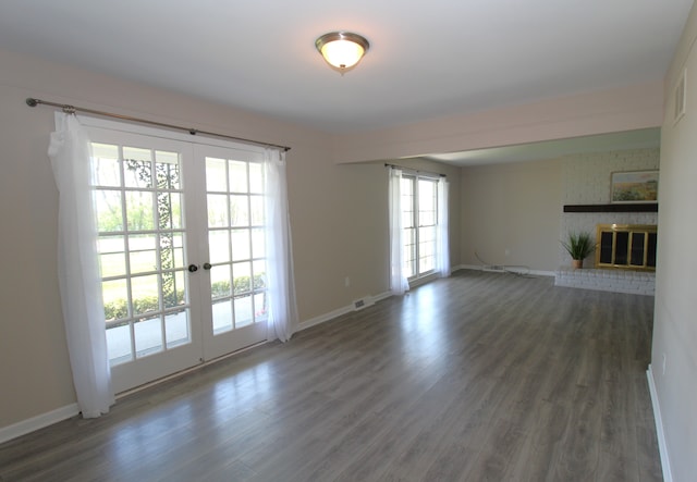 unfurnished living room with french doors, a brick fireplace, wood finished floors, and baseboards