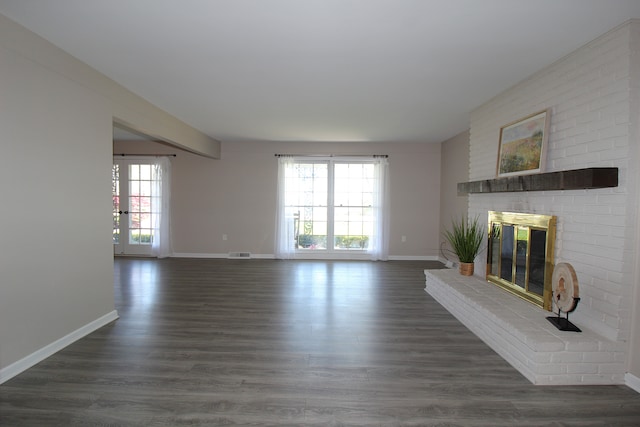 unfurnished living room featuring baseboards, a brick fireplace, and dark wood-style floors