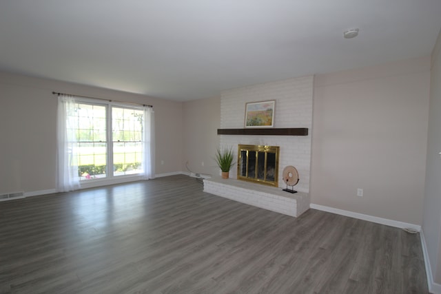 unfurnished living room featuring wood finished floors, a brick fireplace, and baseboards