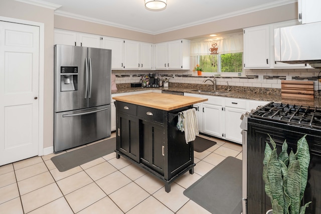 kitchen with appliances with stainless steel finishes, a sink, butcher block counters, dark cabinetry, and white cabinetry