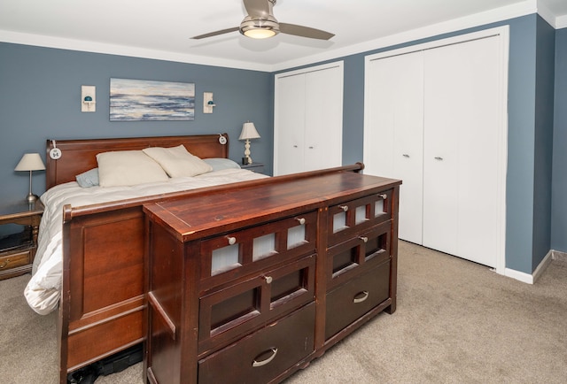 bedroom with multiple closets, light colored carpet, ceiling fan, and baseboards