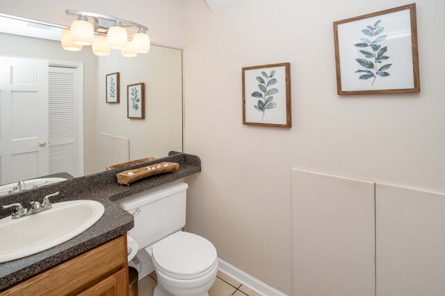 half bathroom with toilet, vanity, tile patterned flooring, and baseboards